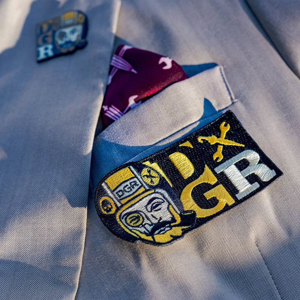 A circular 2026 DGR patch featuring bold lettering and a detailed design in black, white, and red colors.